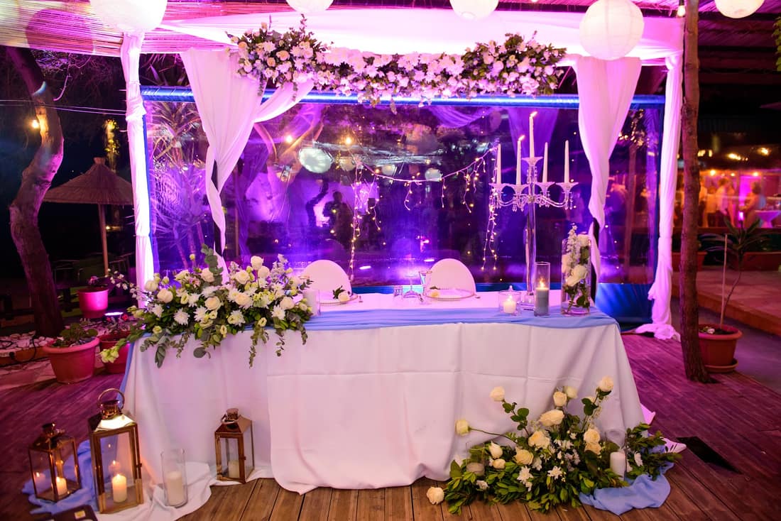 Wedding head table decorated with white flowers and drapes