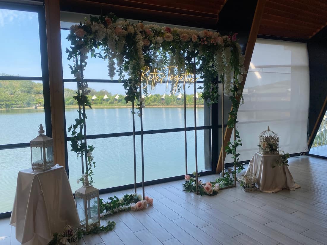Flower arch in front of a glass wall overlooking a lake