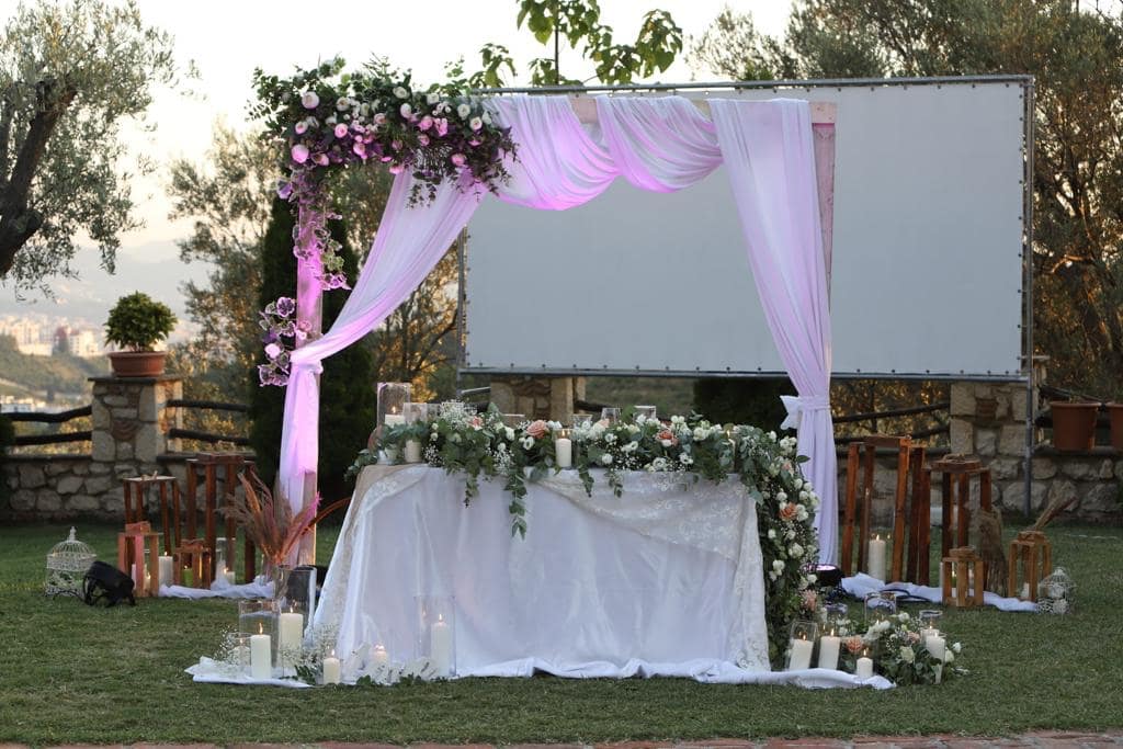 Head table under a draped flower arch on a garden lawn