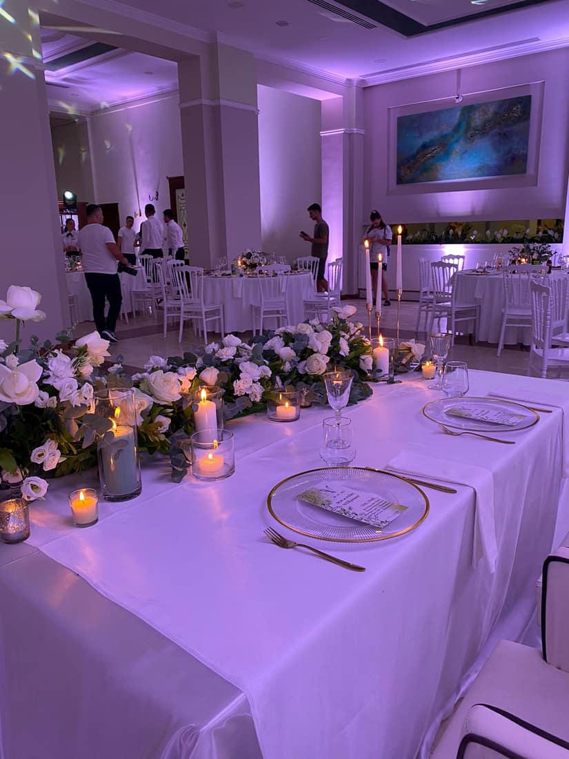 Reception hall in lilac light with white flowers and candles along the table