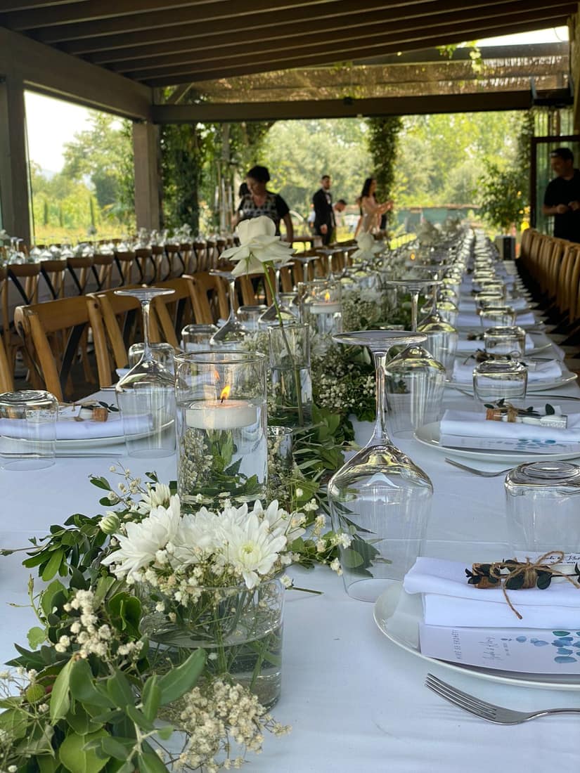 Long table with white flowers, greenery and glassware