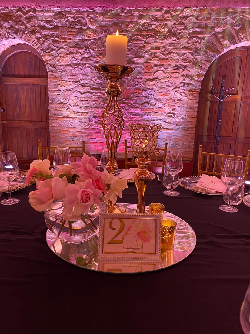 Pink-lit stone room with a round table, roses and candles