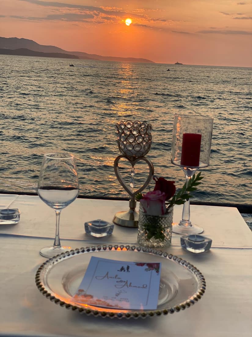 Table for two by the sea at sunset, with a heart ornament and a name card