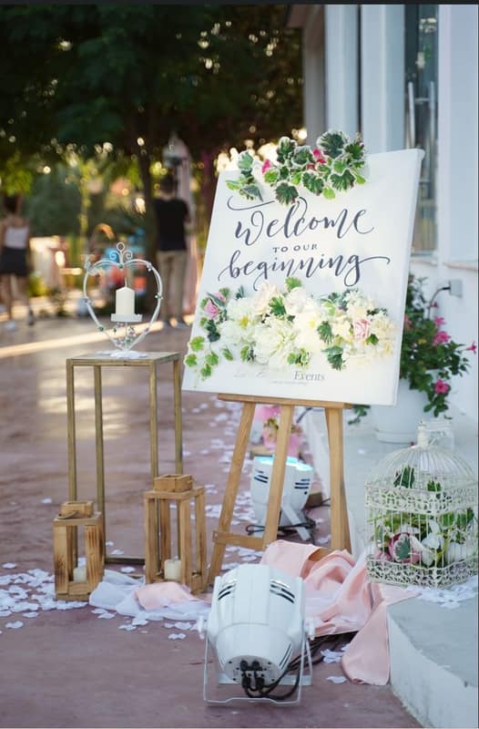 Hand-lettered welcome sign on a gold easel with flowers
